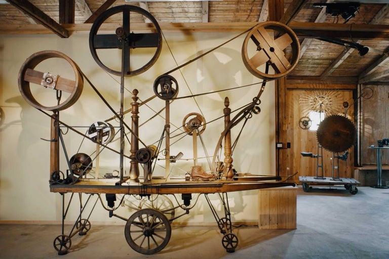 Machine complexe avec roues, courroies et détails en bois dans un atelier
