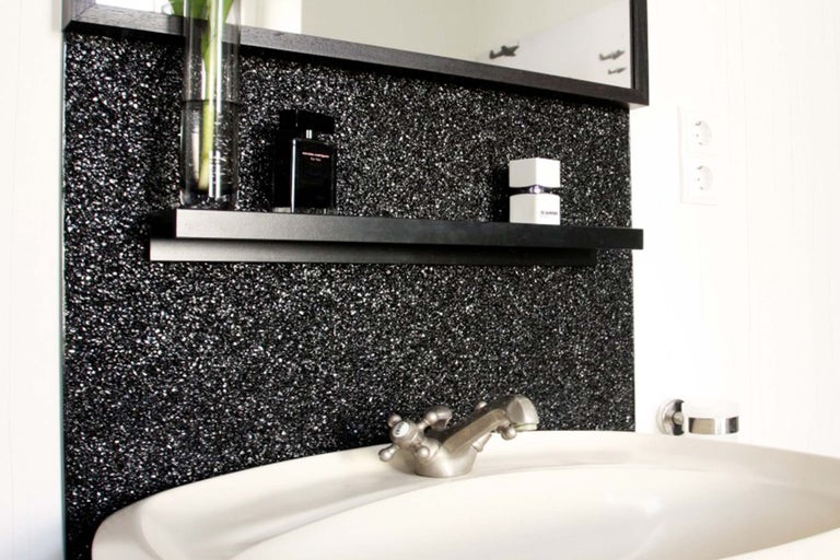Vasque de salle de bains avec robinet, miroir et étagère murale devant un mur scintillant