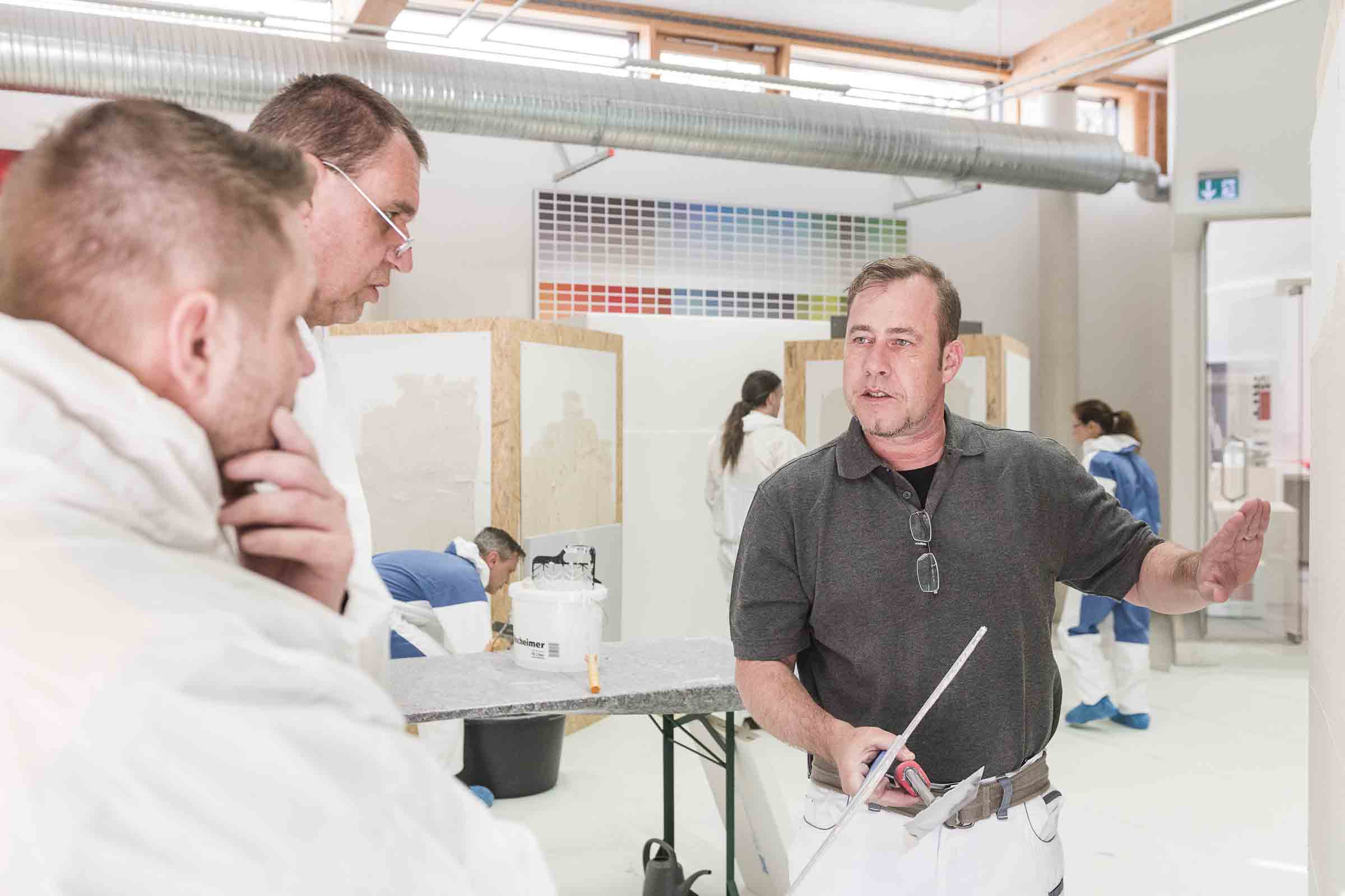 Photo intérieure d'une formation pour plâtriers avec un chef de cours et des participants en tenue de travail