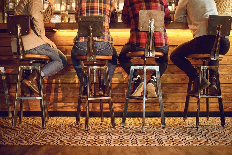 Scène avec des personnes assises sur des tabourets de bar à un comptoir