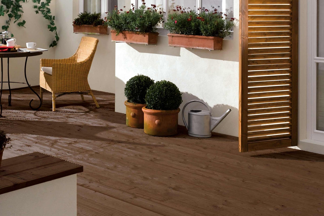 Terrasse mit Holzfliesen, Tisch, Stuhl, Pflanzen und Giesskanne
