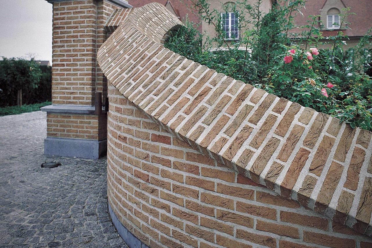 Gebogene Mauer aus Ziegelsteinen in einem Garten