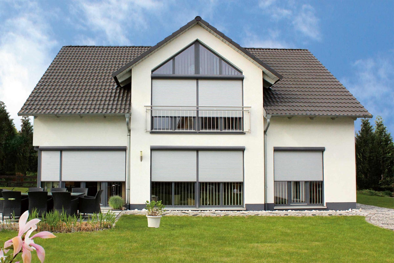 Maison moderne avec volets roulants aux fenêtres pour la protection solaire et l'intimité.