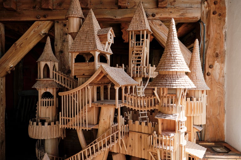 Gros plan sur une maquette complexe de cabane en bois avec des tours, des escaliers et des toits en bardeaux.
