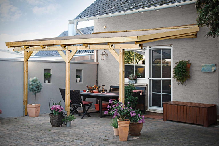 Terrasse avec terrasse en bois, table de jardin et chaises devant un mur de maison
