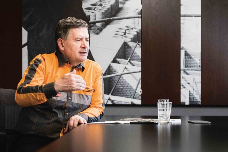 Ein Mann in Arbeitskleidung sitzt an einem Konferenztisch.