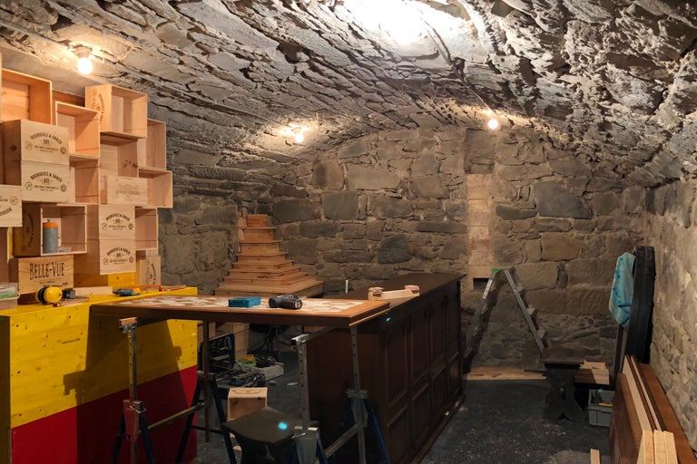 Atelier dans une cave avec des pierres, des caisses en bois et des outils