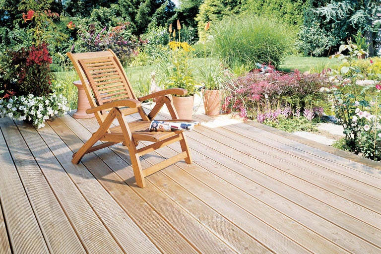 Terrasse en bois avec chaise longue de jardin et parterres de fleurs dans le jardin