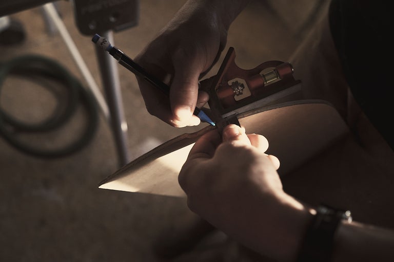 Eine Person markiert mit einem Bleistift und einem Winkel eine Holzplatte.