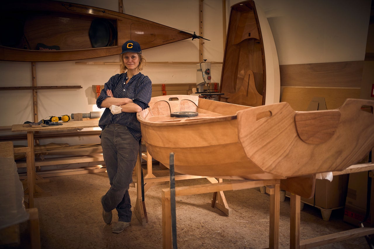 Atelier avec femme et un bateau en bois en construction