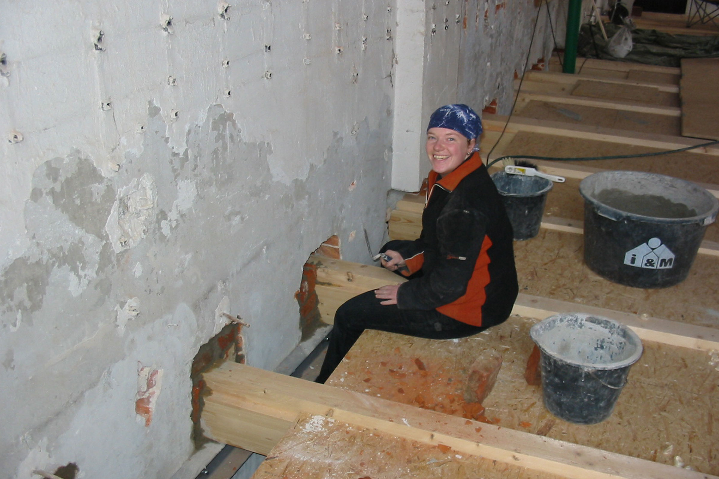 Femme assise sur des poutres en bois avec des outils et des seaux pendant les travaux de rénovation