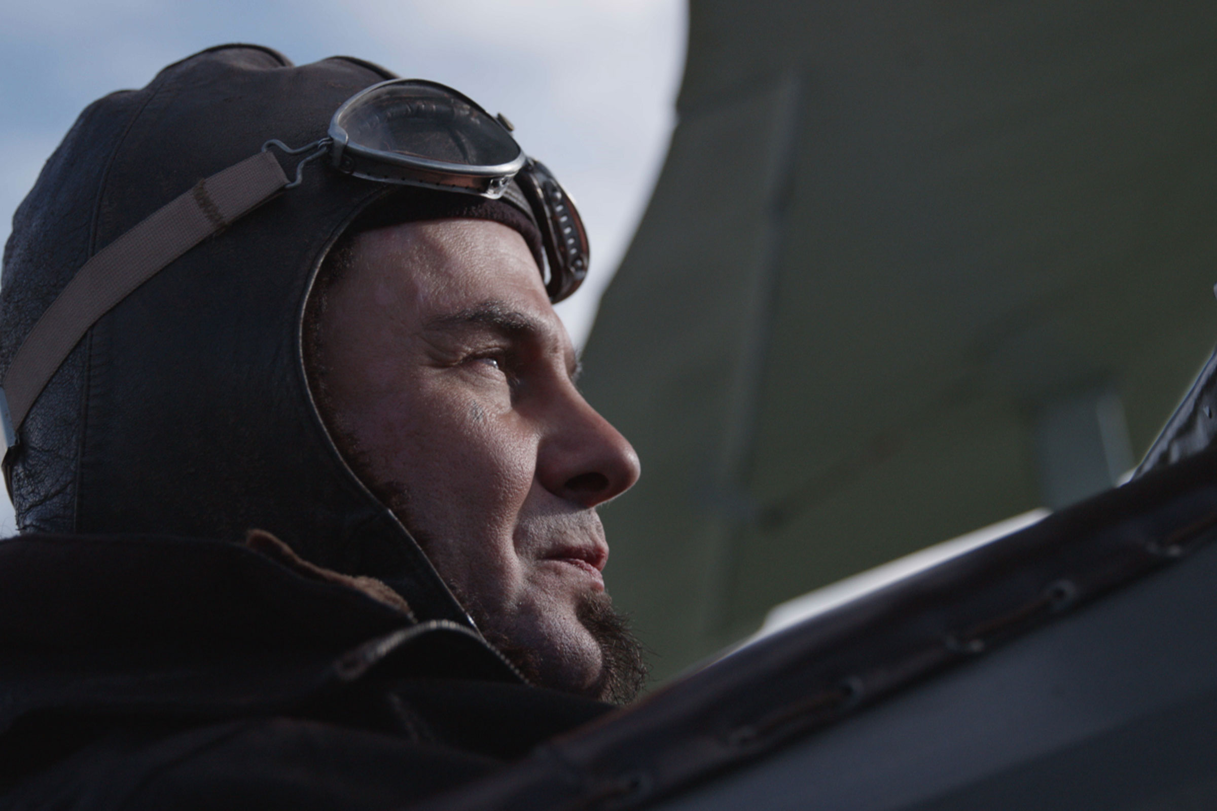 Homme portant un bonnet d’aviateur et des lunettes regardant au loin