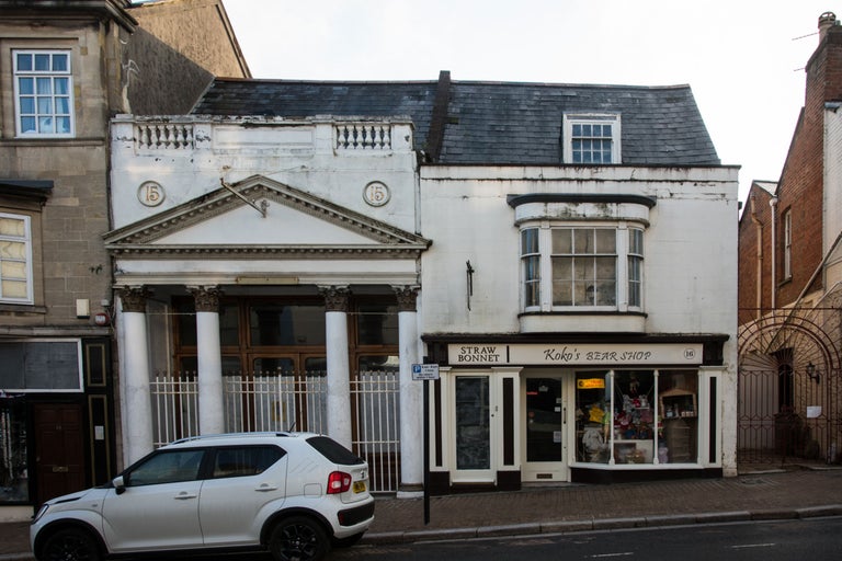 Vue d'un bâtiment avec les numéros 15 et 16 abritant un magasin de chapeaux de paille et une boutique d'ours en peluche