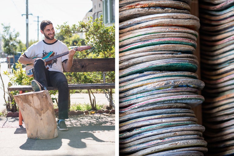 Aufnahme eines Mannes, der Gitarre spielt und neben einem Stapel recycelter Skateboards auf einer Bank sitzt