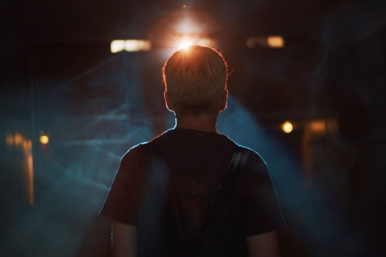 Vue arrière d'une personne dans une pièce sombre avec éclairage