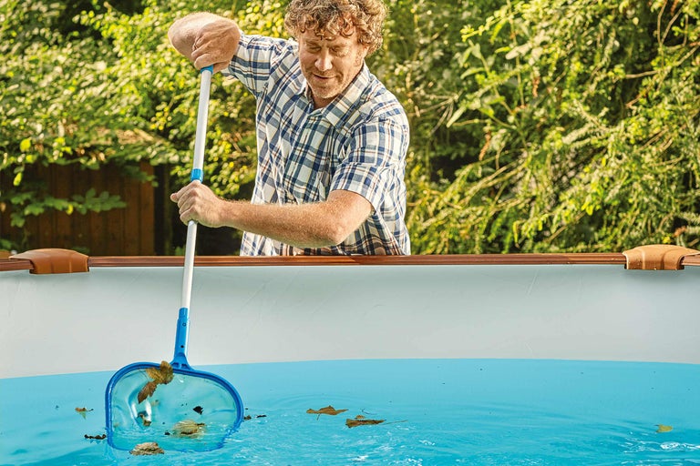 Mann reinigt Pool mit Kescher von Blättern