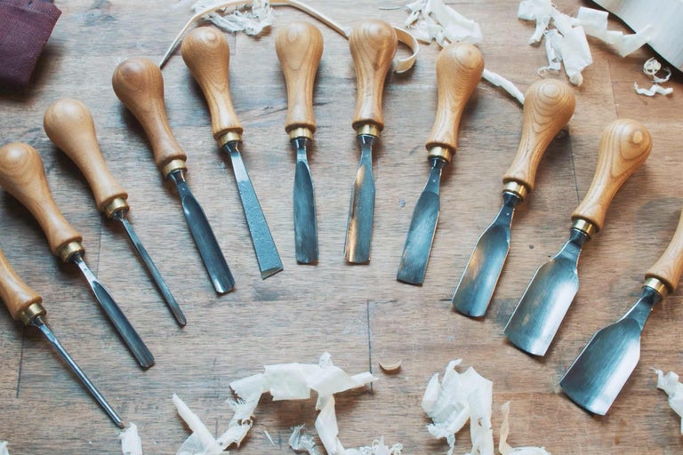 Une collection de ciseaux à bois avec des manches en bois sur une surface en bois.