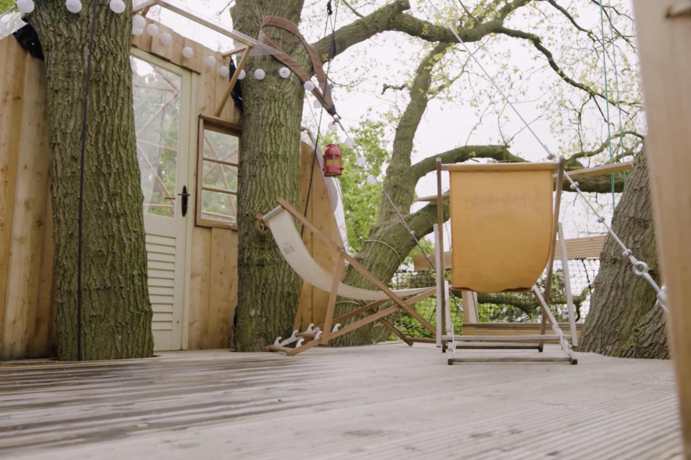 Cabane dans les arbres avec terrasse en bois et chaises longues