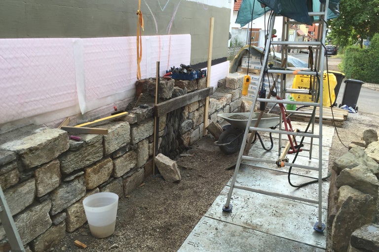 Baustelle mit Steinmauer, Leiter und Werkzeugen
