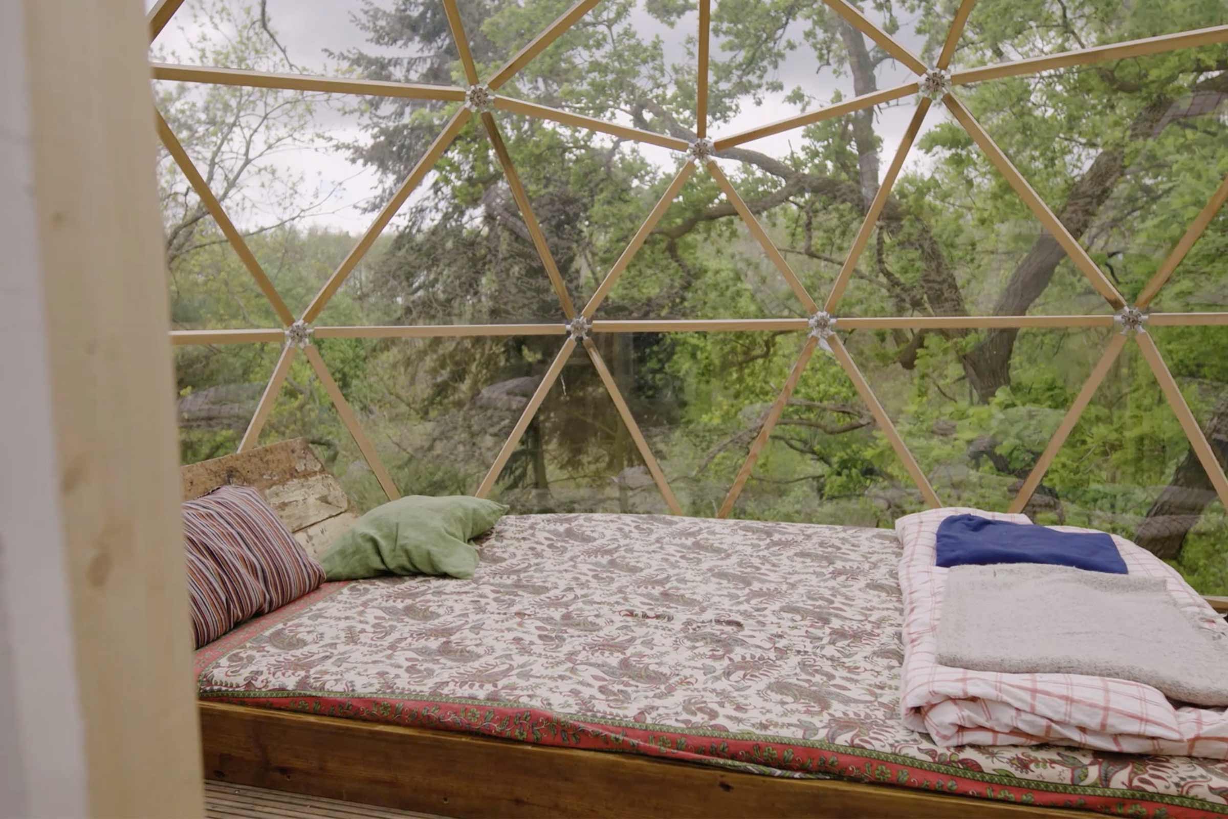Intérieur d'un dôme géodésique avec lit et vue sur la nature