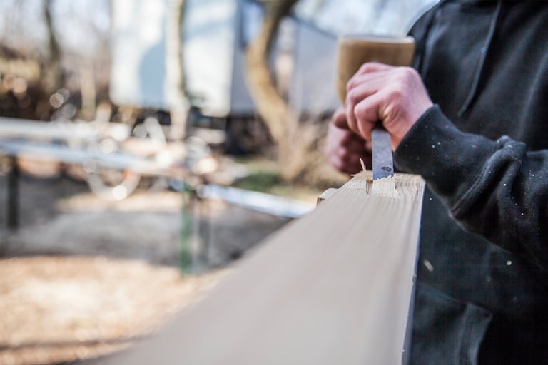 Artisan travaillant le bois avec un ciseau et un marteau