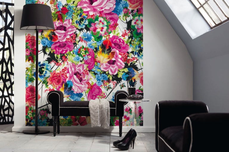 Wohnraum mit floral gemusterter Tapete, Stehlampe und Sitzmöbeln.