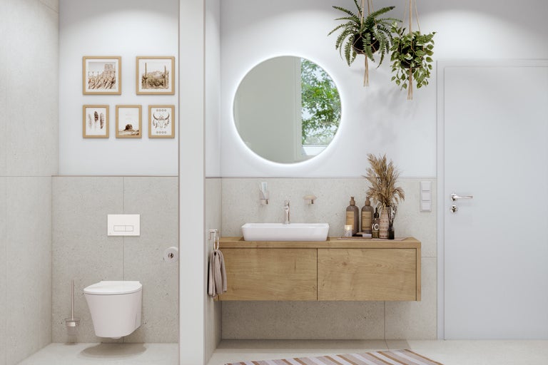 Salle de bains lumineuse avec meuble sous-lavabo, toilettes et miroir rond