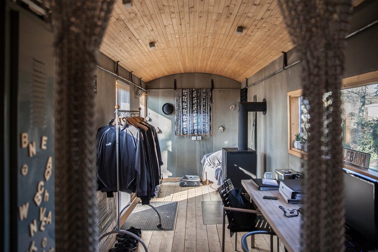 Vue intérieure d'un bureau avec un poêle à bois, un bureau et un portant à vêtements.