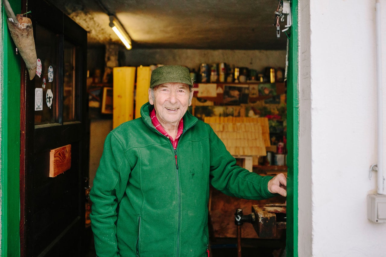 Un homme avec une casquette et une veste en polaire se tient à la porte d'un atelier.