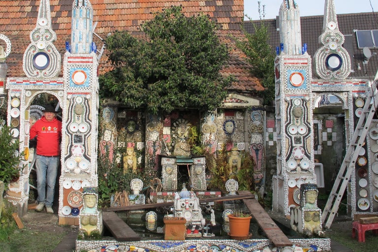 Aussenansicht eines mit Keramik und Geschirr verzierten Hauses mit einem Mann im Eingang