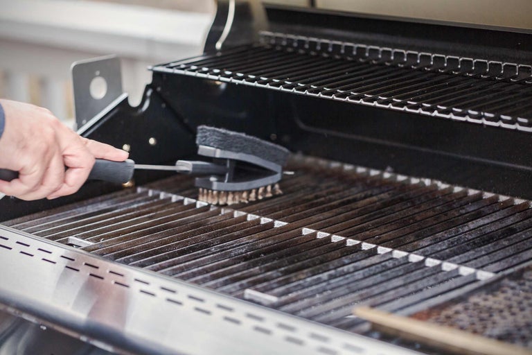 Eine Grillbürste reinigt einen Grillrost.
