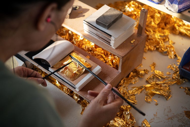 Doreuse travaillant avec de la feuille d'or et des outils de dorure