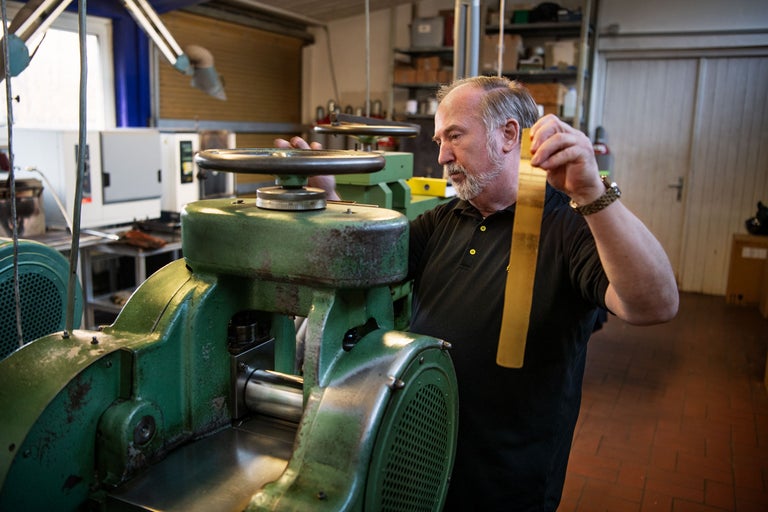 Un homme actionne une machine à laminer dans un atelier