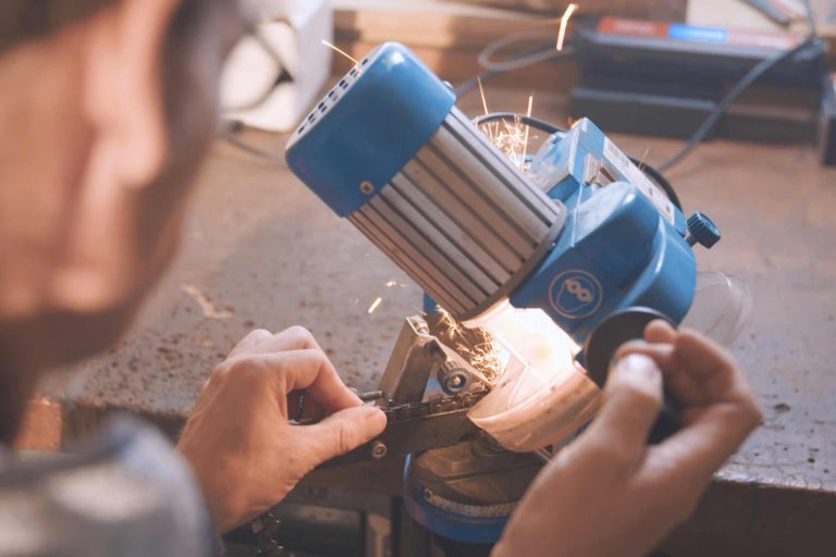 Eine Person schärft mit einem Kettenschärfgerät eine Kette