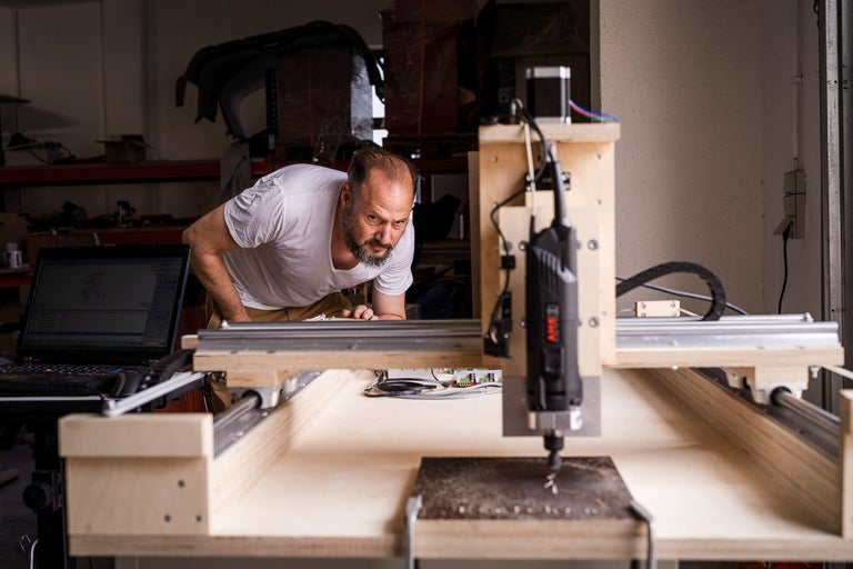 Homme utilisant une fraiseuse CNC avec un ordinateur portable dans un atelier