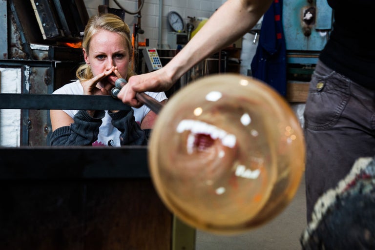 Glasbläserin formt Glas mit einer Blasform in einer Werkstatt