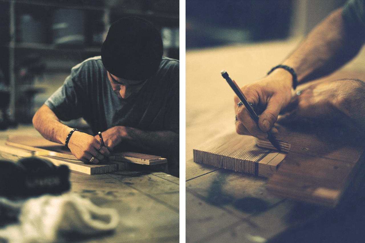 Un homme dessine avec un crayon sur une planche de bois