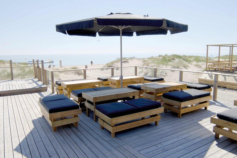 Espace extérieur avec plancher en bois, parasol et groupes de sièges avec coussins