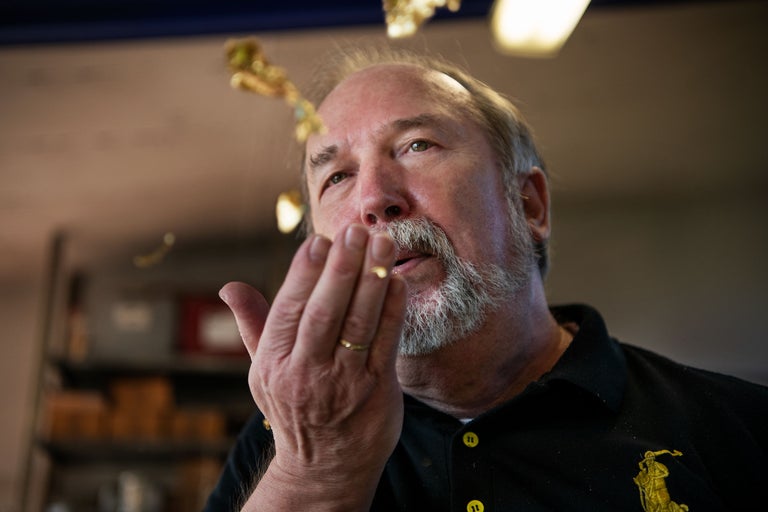 Un homme souffle des feuilles d'or de sa main