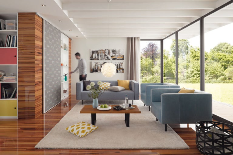 Helles Wohnzimmer mit Sofa, Sesseln, Teppich und Blick in den Garten