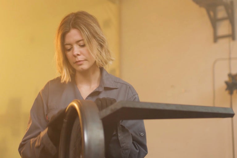 Femme en vêtements de travail travaillant une pièce métallique