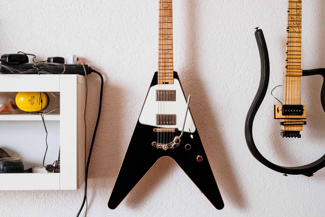 Un mur porte une guitare électrique en forme de V et une autre guitare avec un cadre comme corps.