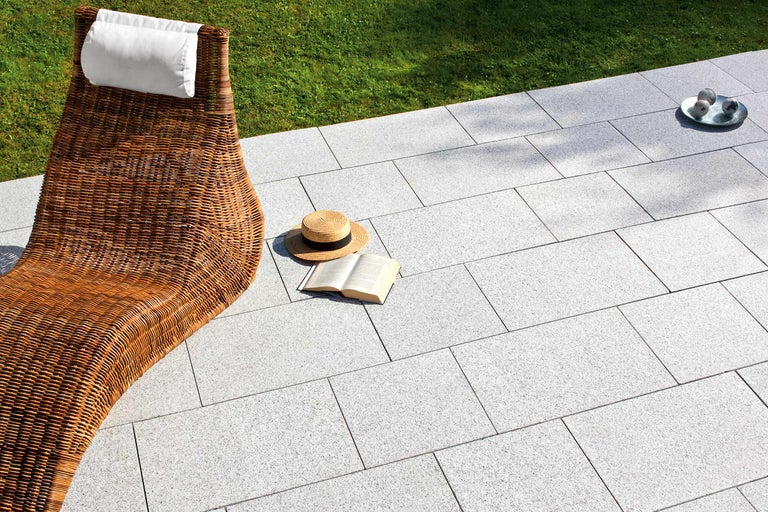 Scène de jardin avec chaise longue en rotin, pavés et accessoires d'été