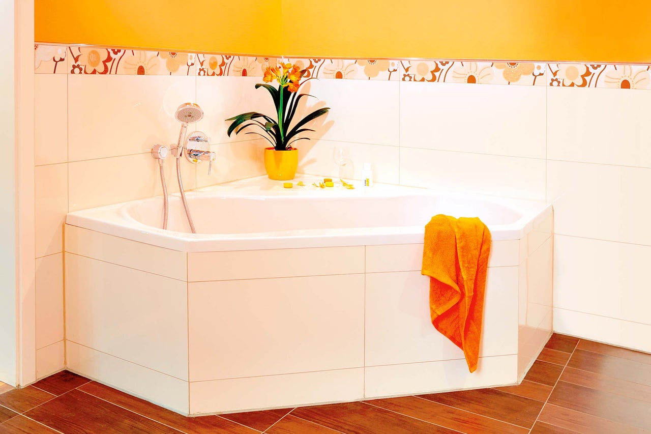 Eckbadewanne in einem Badezimmer mit Fliesen und Dekorationen