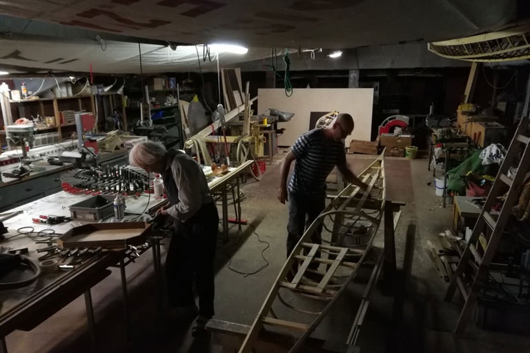 Atelier avec personnes, bateau en bois et outils