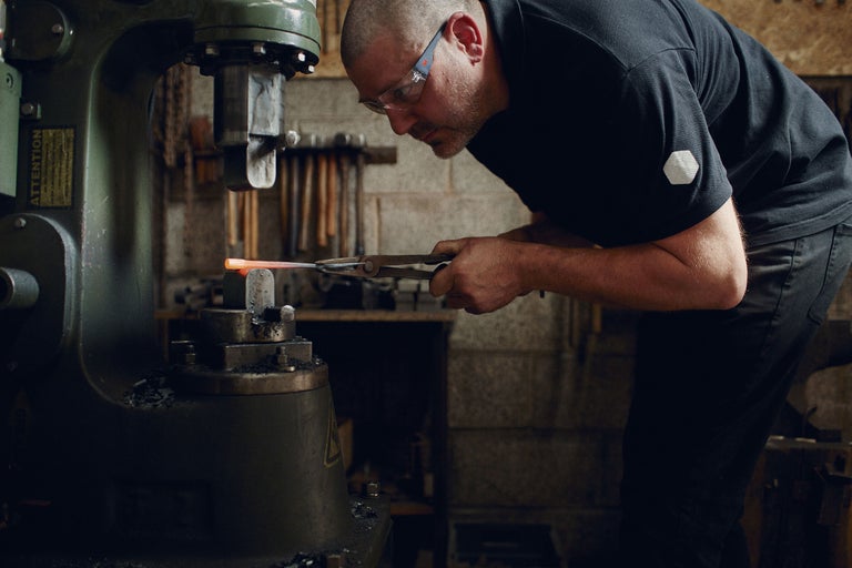 Un forgeron travaille le métal incandescent avec une forge.