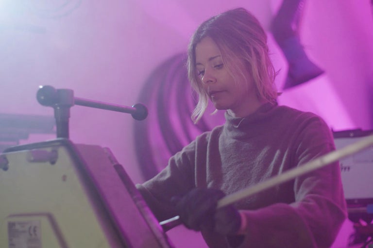 Une femme utilise une cintreuse à tubes dans un atelier.