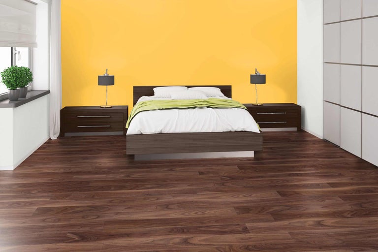 Chambre avec lit, tables de chevet, lampes, sol stratifié et mur jaune