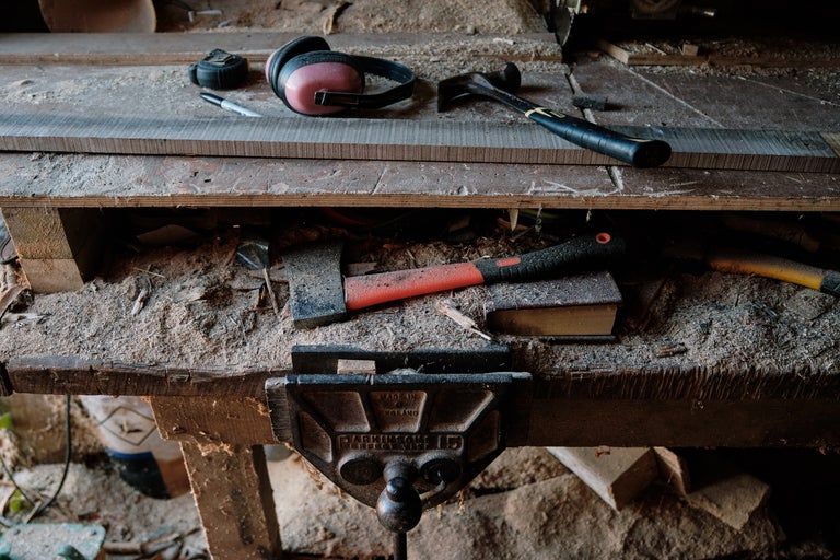 Établi avec outils tels que marteau, hache, étau, stylo, mètre ruban et protection auditive