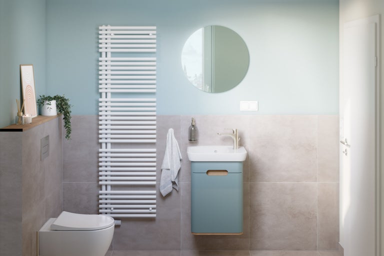 Helles Badezimmer mit Toilette, Waschbeckenunterschrank, Heizkörper und Spiegel